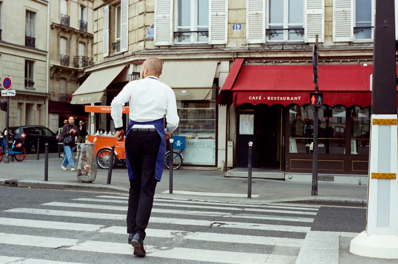 A waiter runs across the road to his cafe in Paris