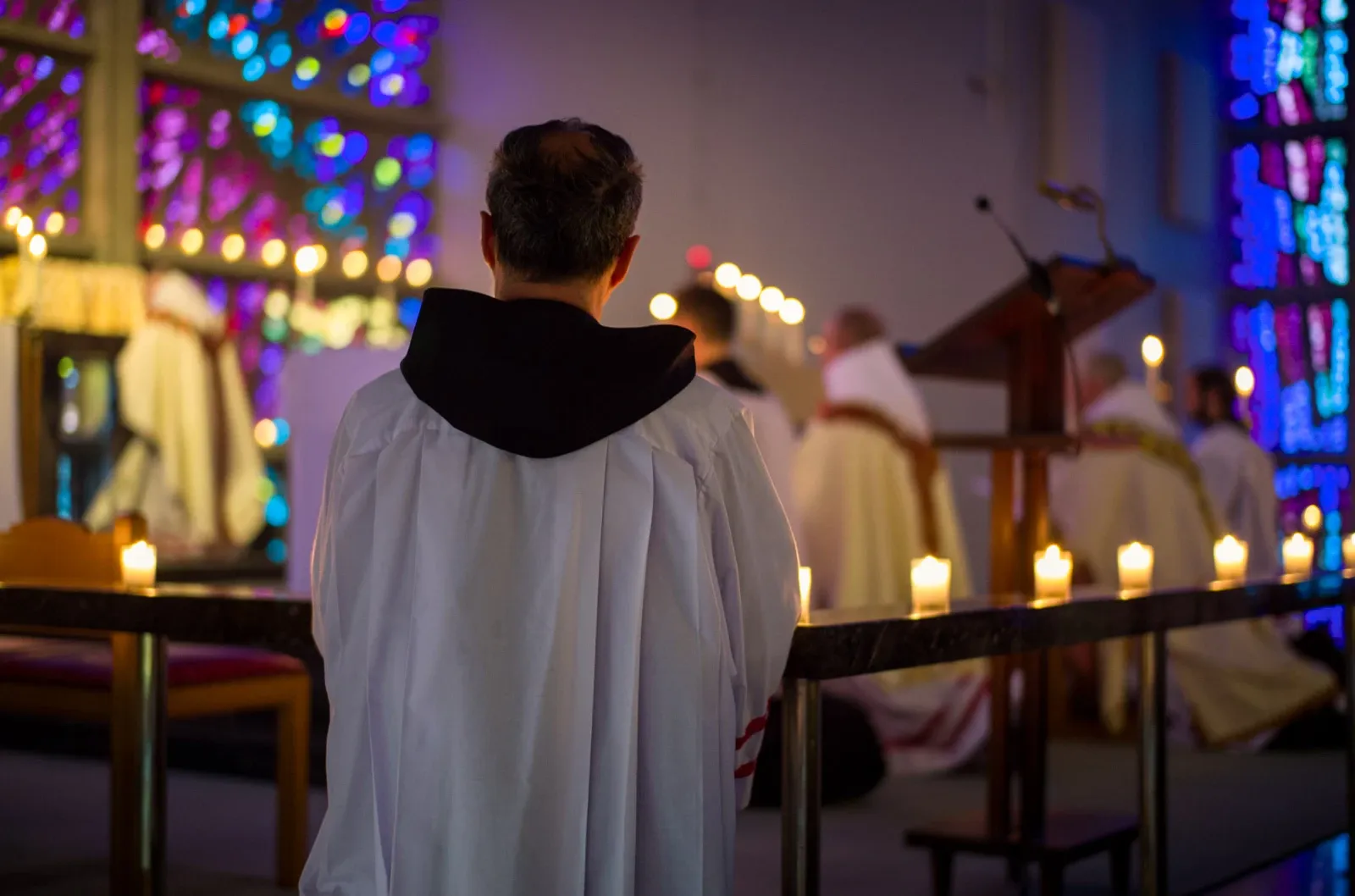 A close up photo of a Monk surrounded by candlelight during Maundy Thursday