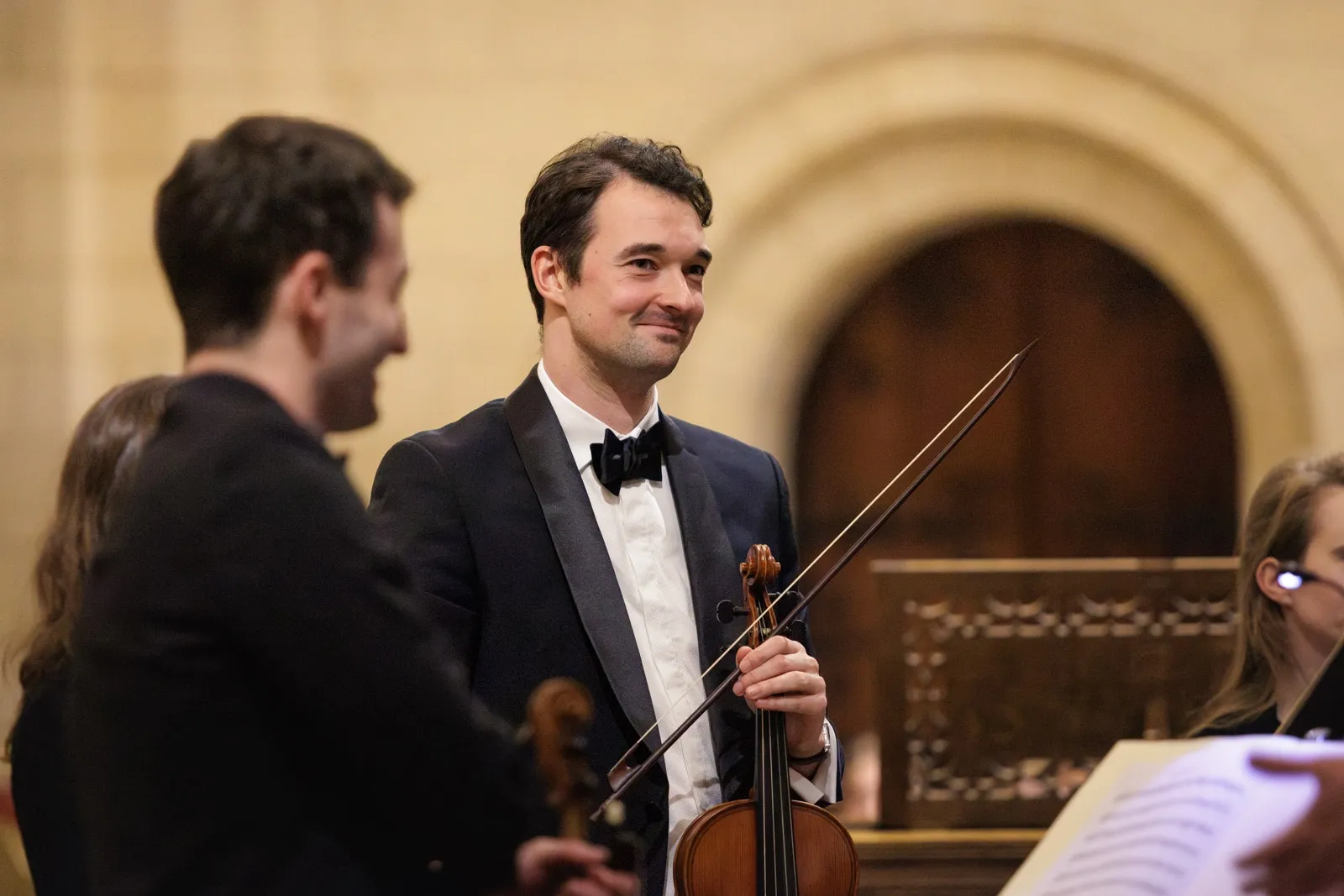 A musician stands with his violin accepting applause