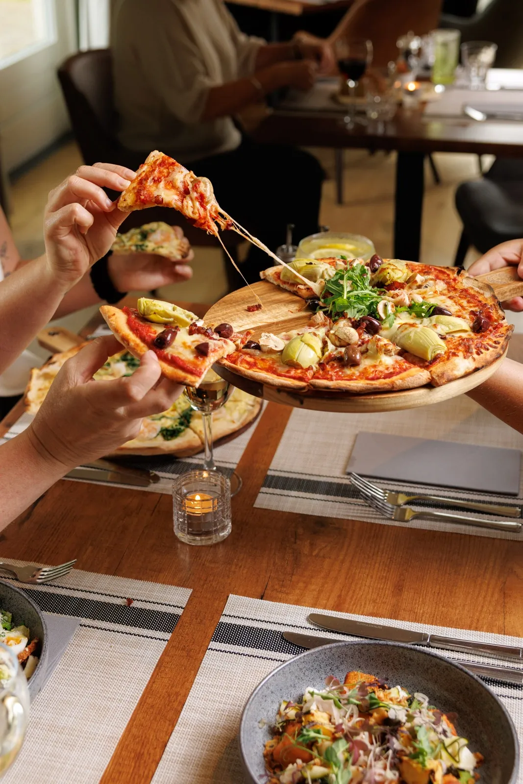 A group of friends share a pizza at a dining table