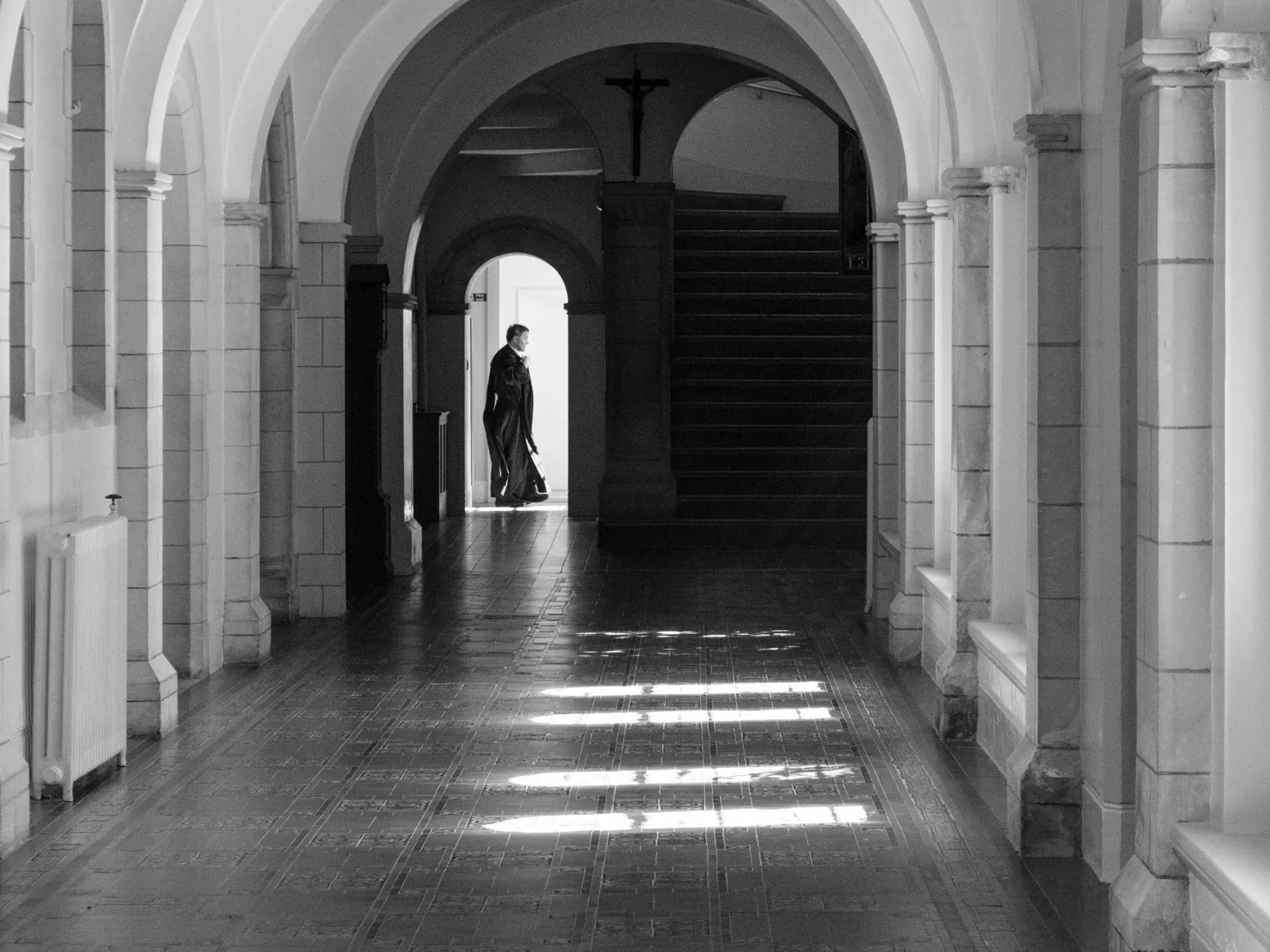 A monk passes a doorway inside a cloister