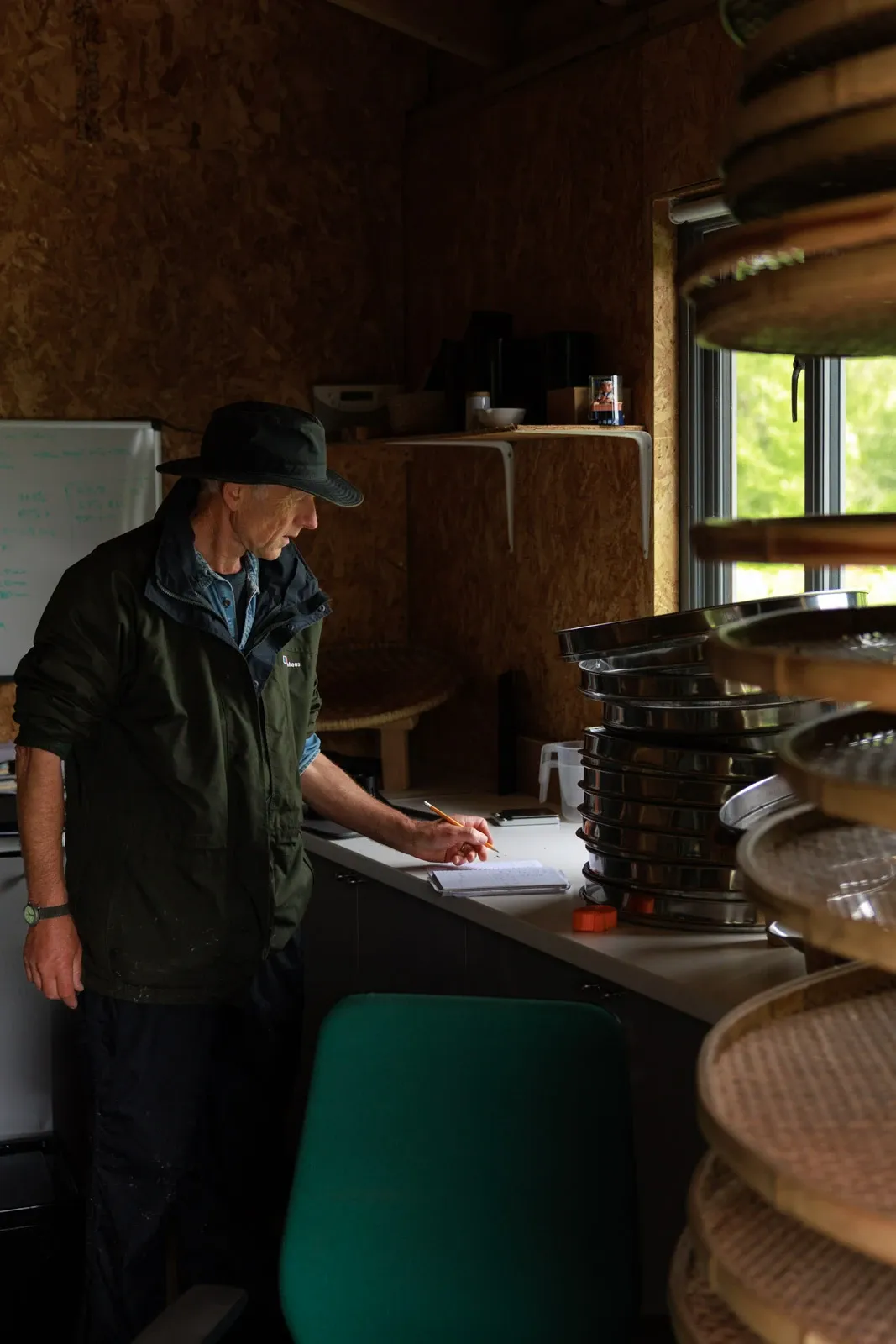 Tea farmer Jo writes the weight of the day's tea yield inside his lab by a window