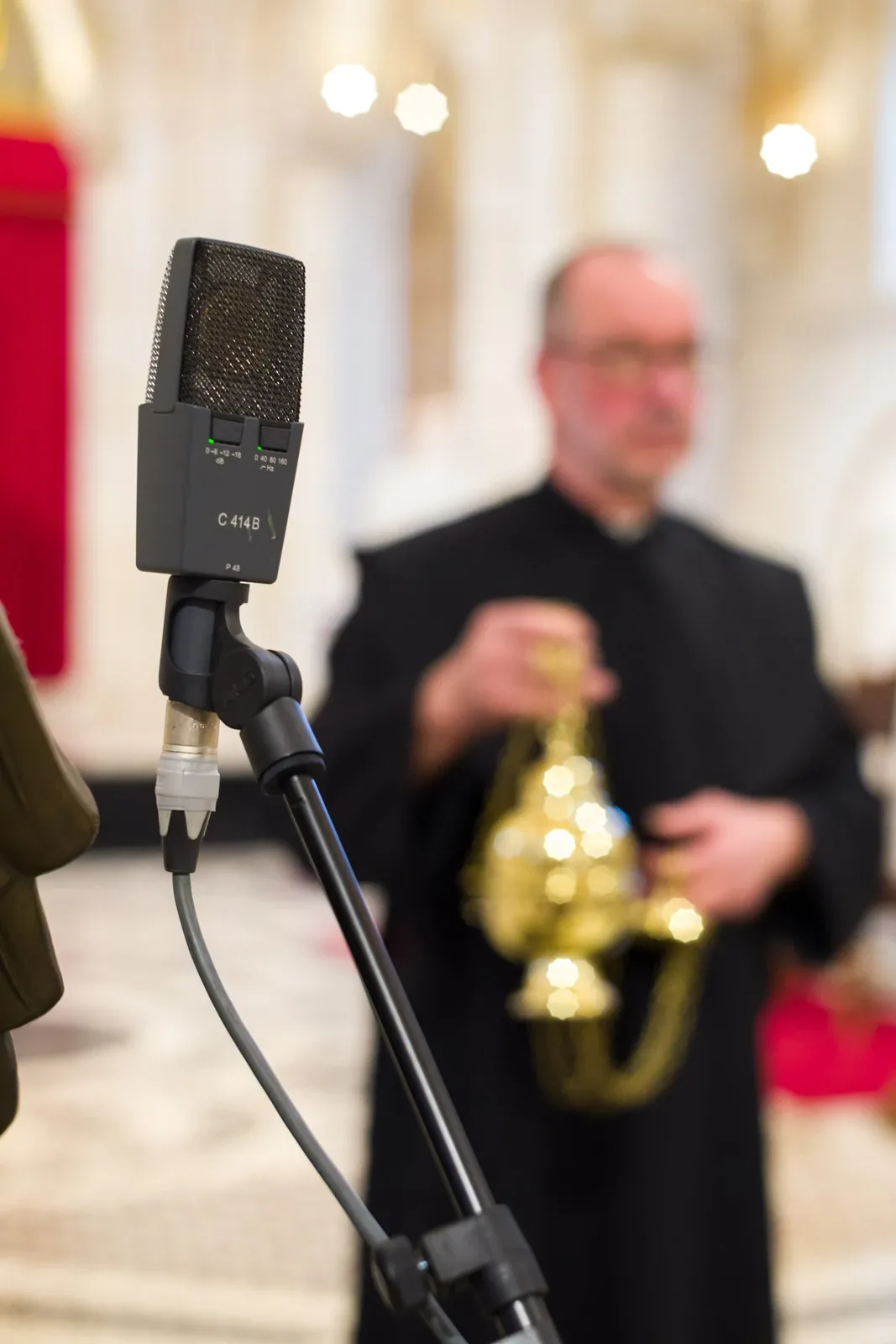 A microphone records a monk swinging a censer