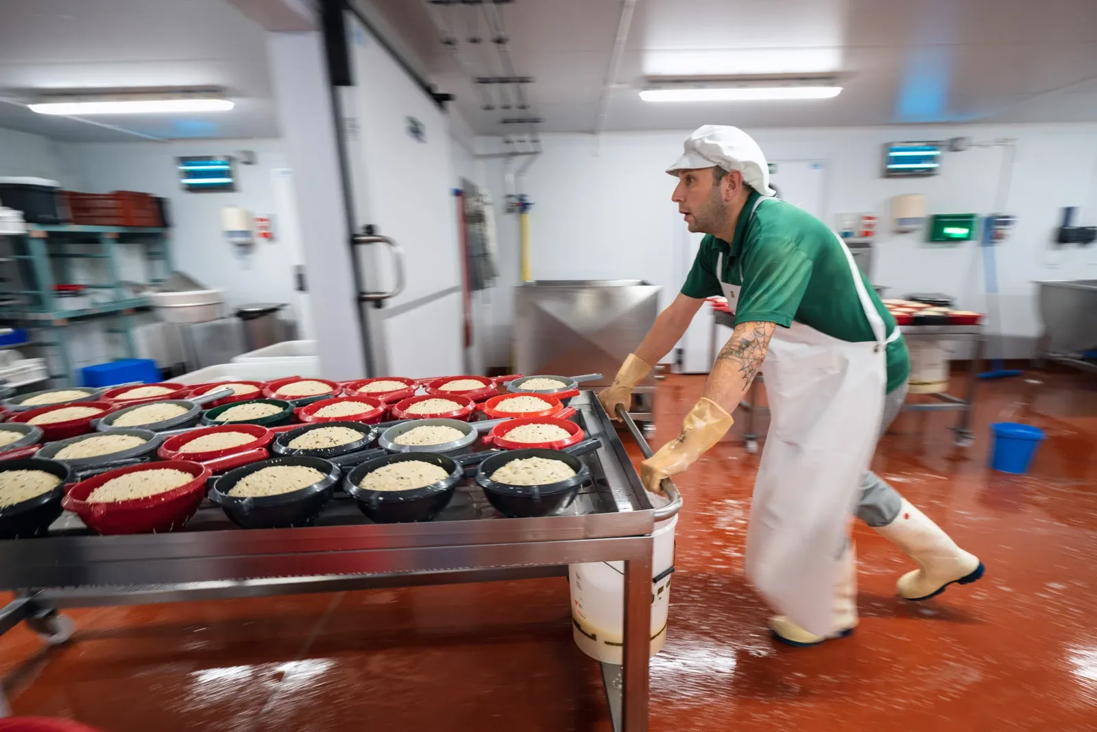 A cheesemaker rushes to push a trolley of cheese through the dairy