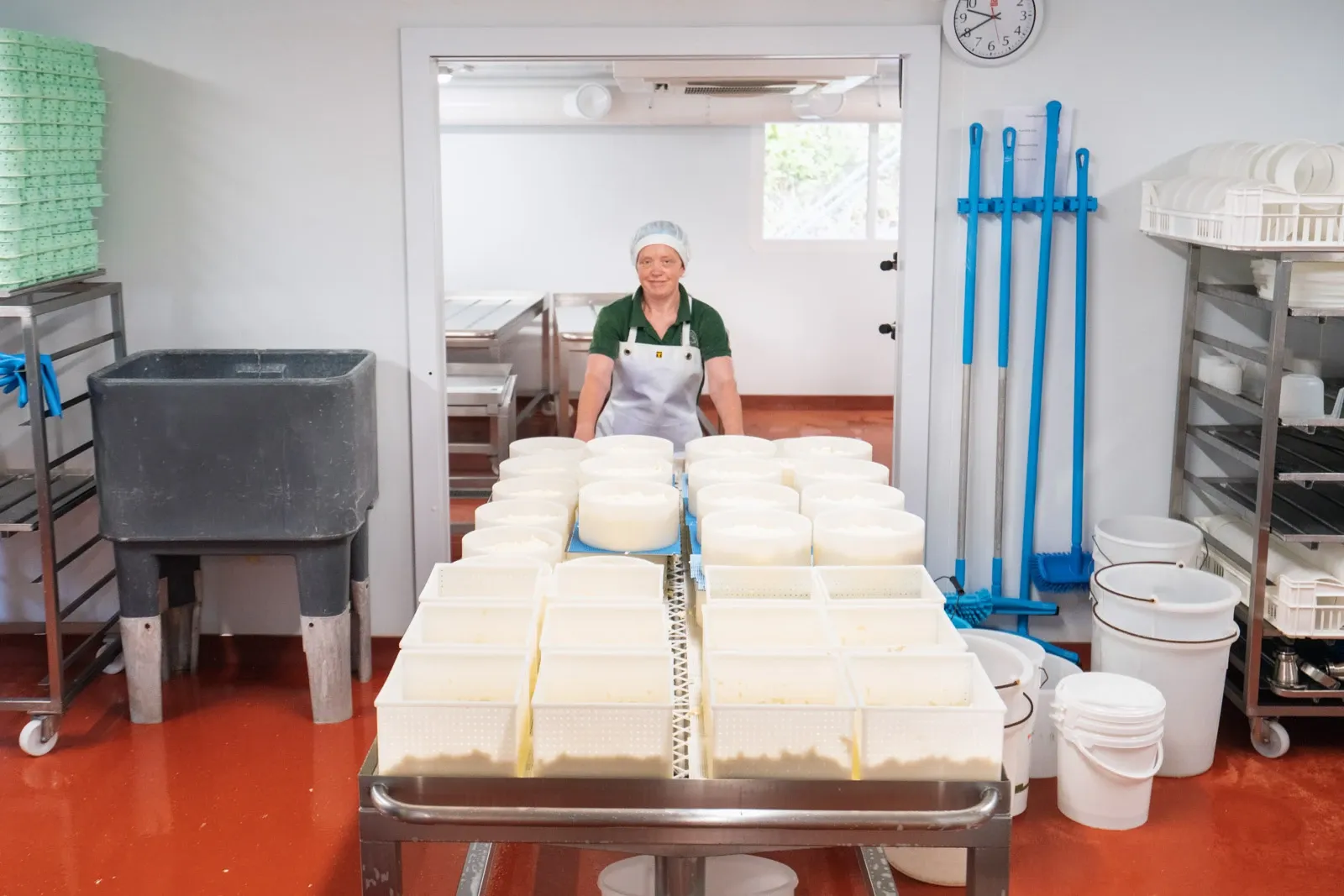 A cheesemaker pulls a trolley of cheese into a cold room